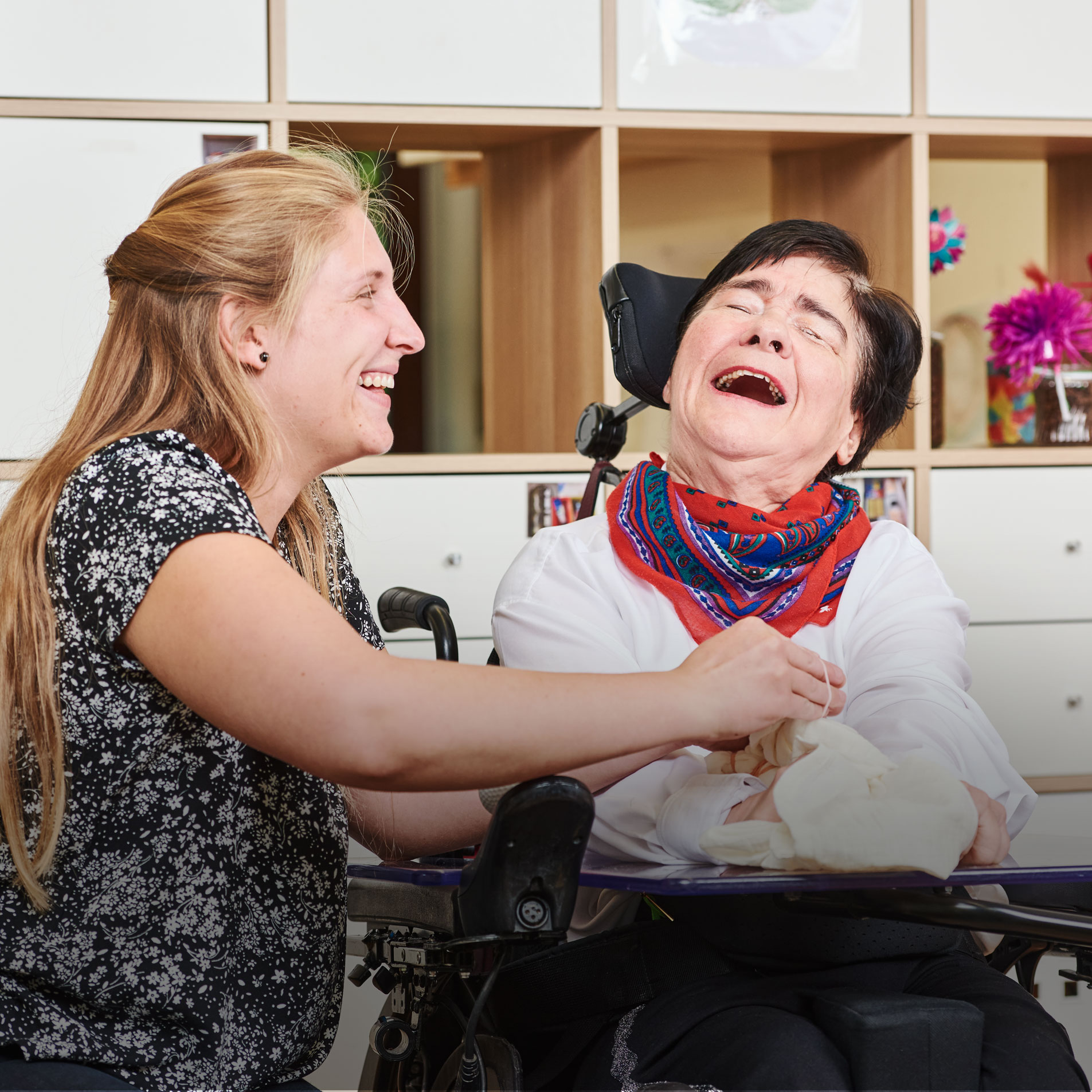 Augustinum Förderbereiche und Seniorentagesstätte Eine Mitarbeiterin und eine Klientin des Augustinum Förderbereiches lachen gemeinsam