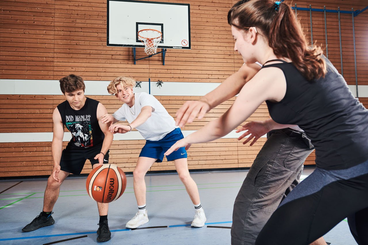 Sportunterricht Schüler*innen spielen Basketball im Sportunterricht