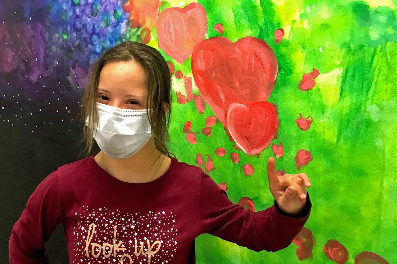 Kunstprojekt Ein Mädchen steht vor einer bunt bemalten Wand