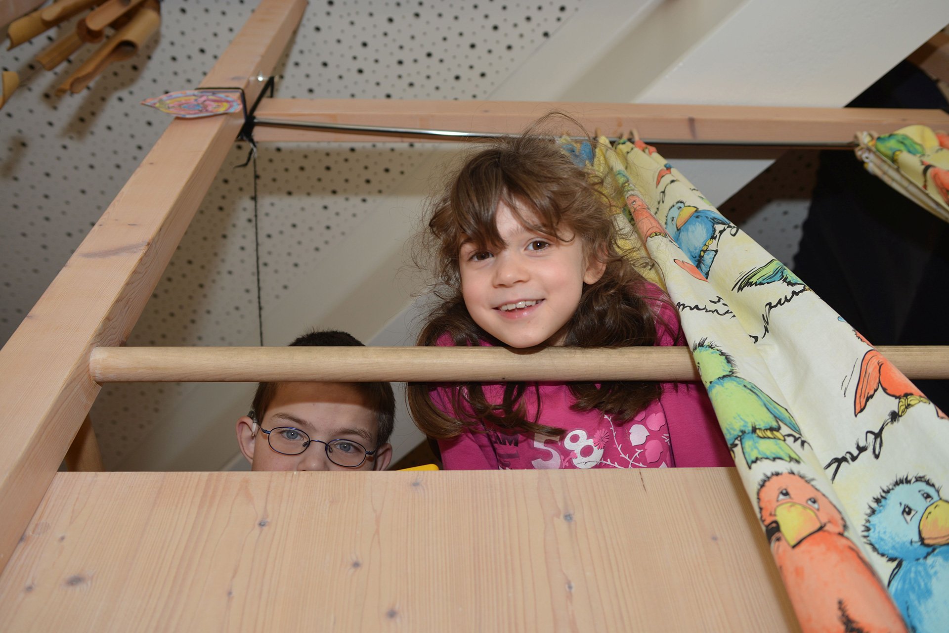 Räume für Geborgenheit in der Augustinum Kindertagesstätte Zwei Kinder schauen von ihrem Lieblingsplatz aus nach unten in die Kamera