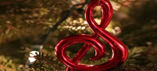 Notenschlüssel und Christbaumkugel vor Tannenzweigen Notenschlüssel und Christbaumkugel vor Tannenzweigen