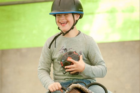 Augustinum Therapeutisches Reiten Ein Junge beim therapeutischen Reiten