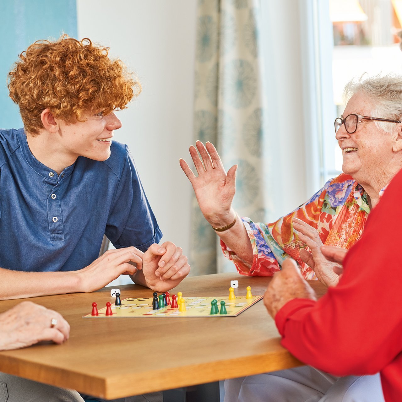 Augustinum Berchtesgadener Land Tagespflege Zwei Seniorinnen und ein Pfleger des Augustinum spielen gemeinsam ein Brettspiel