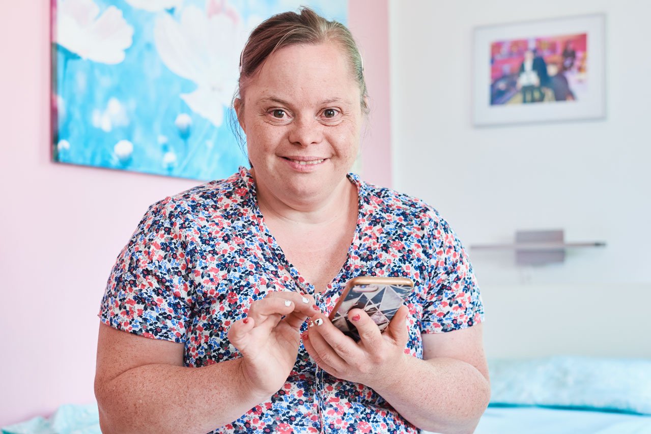 Rückzugsmöglichkeit Eine Frau mit einem Handy in der Hand sitzt auf einem Bett