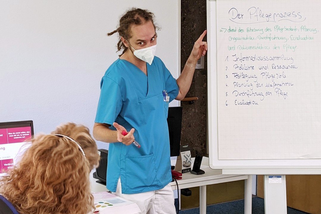 Augustinum Klinik Pflegeausbildung Ein Pfleger erklärt den Pflegeprozess während sich eine Frau Notizen dazu macht