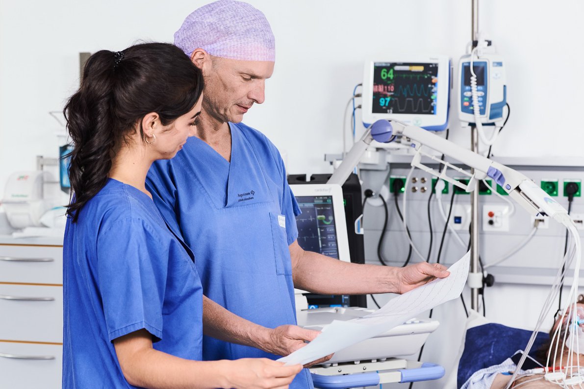Chest Pain Unit - CPU Bild eines Arztes und einer Pflegerin bei der Kontrolle des EKGs eines Patienten mit einem Link zur Chest Pain Unit der Augustinum Klinik