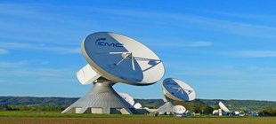 Erdfunkstelle Raisting auf grüner Wiese und blauem Himmel Satellitenschüsseln auf Wiese blauer Hintergrund