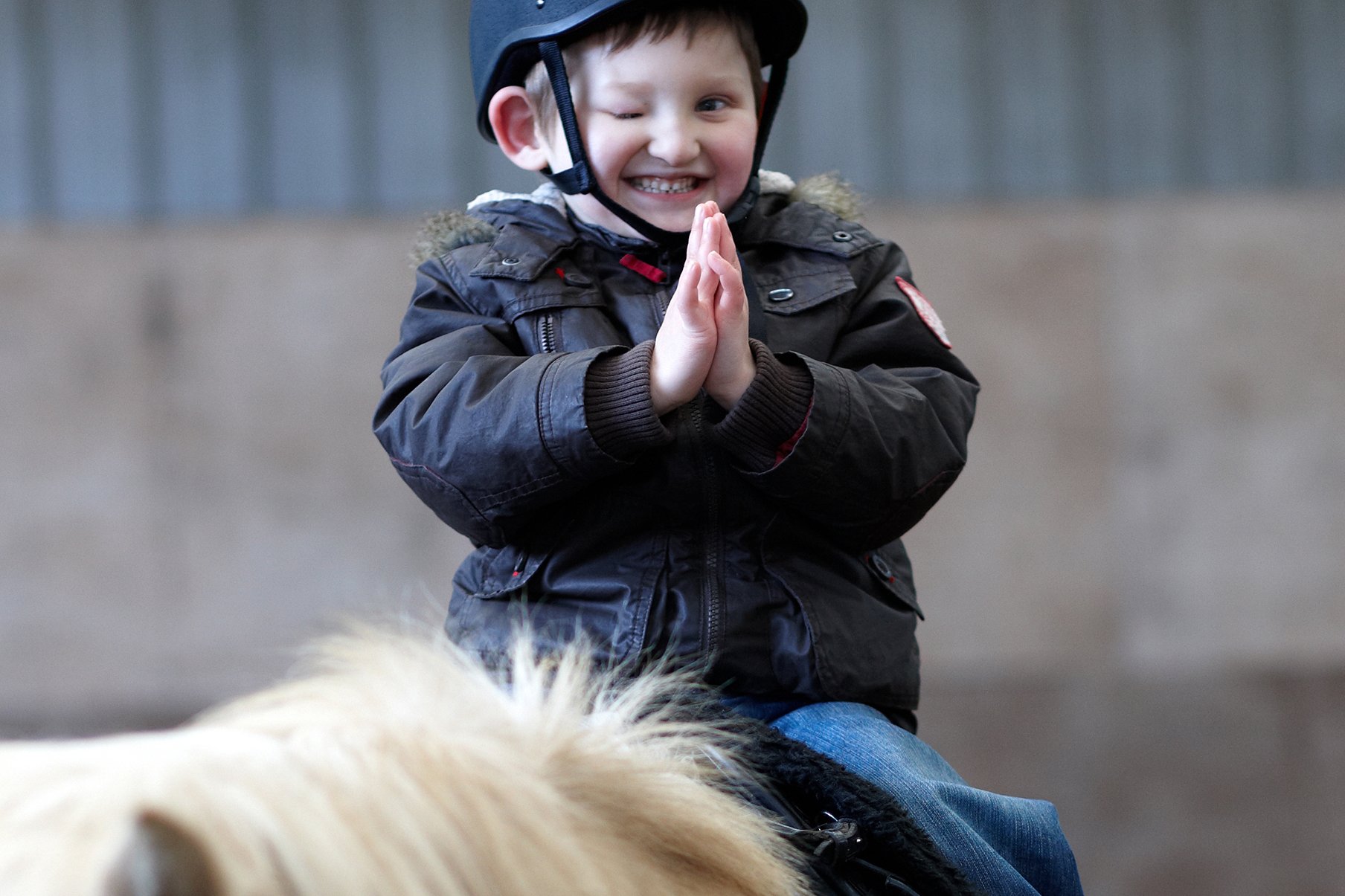 Therapeutisches Reiten in den Augustinum Frühförderstellen Behinderter Junge mit Reithelm auf einem Pferd