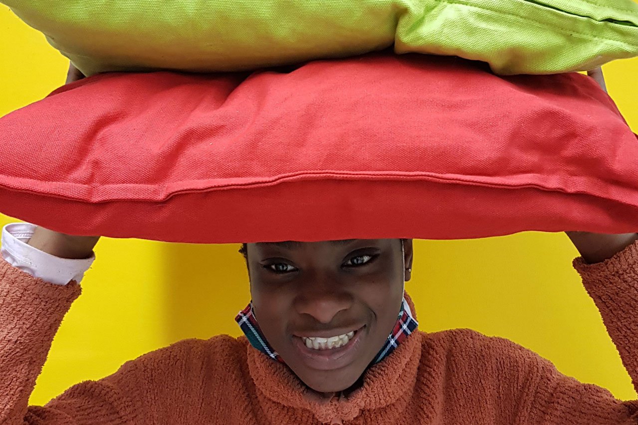 Mädchen mit Kissen Ein Mädchen trägt bunte Kissen auf ihrem Kopf