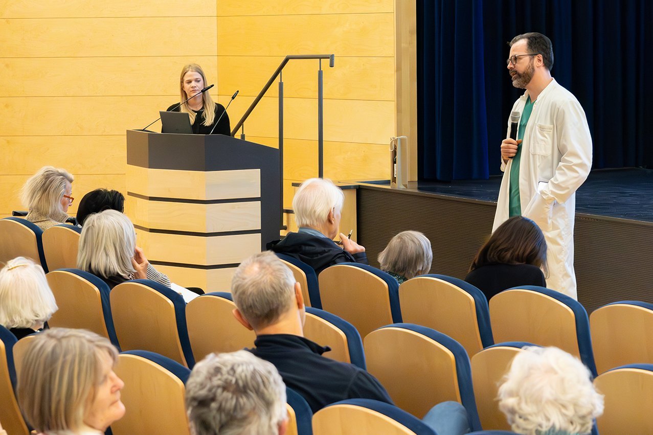 Augustinum Klinik Herzwochen Fragen Die Referentin Dr. Wesseli und der Chefarzt Dr. Husser stehen mit Mikrofonen vor dem Publikum