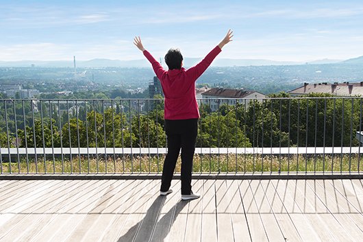 Japanisches Qi-Gong Frau mit ausgebreiteten Armen auf einer Dachterrasse