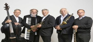 Forsche Pädagogen, feiner Swing Fünf Musiker einer Jazz- und Swingband stehen nebeneinander und präsentieren ihre Instrumente: Kontrabass, Keyboard, Trompete, Saxophon und Gitarre.