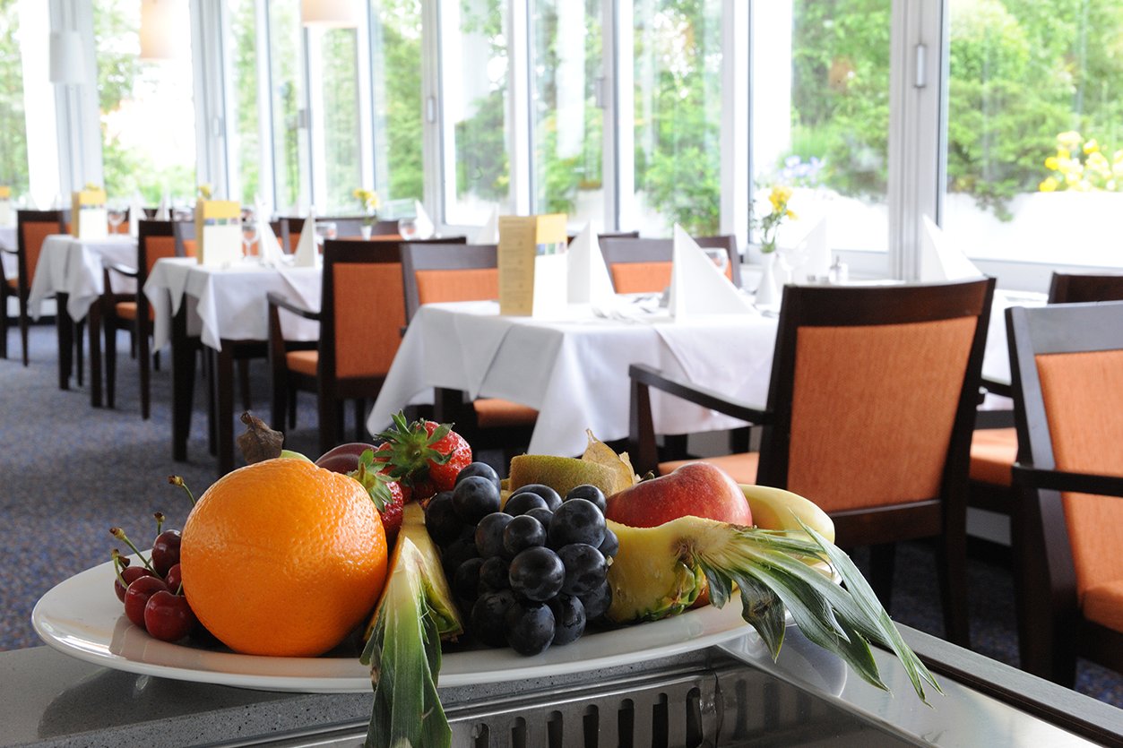 Augustinum Seniorenresidenz Dießen Obstkorb Slider Ein Obstkorb mit den gedeckten Tischen des Restaurants im Hintergrund