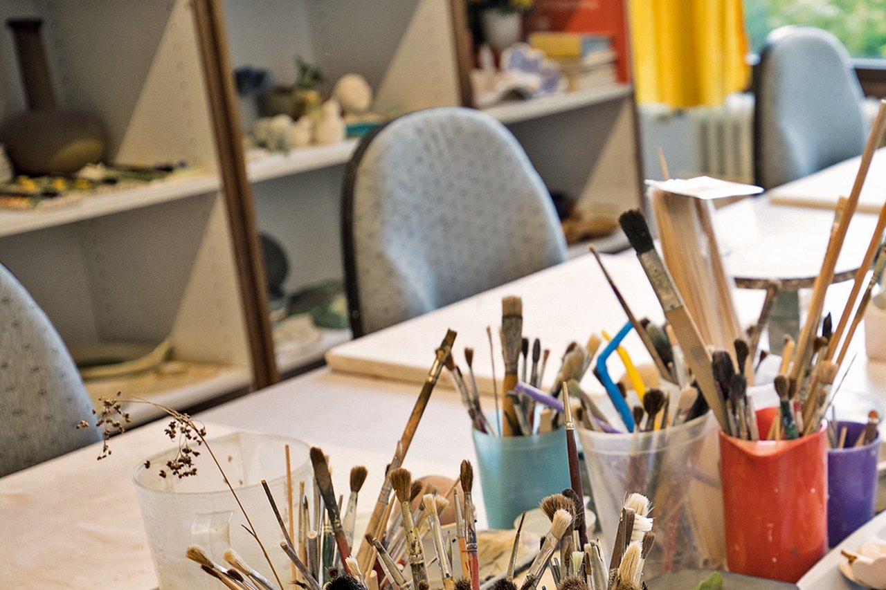 Malkurs Pinseln in Bechern auf Tischen