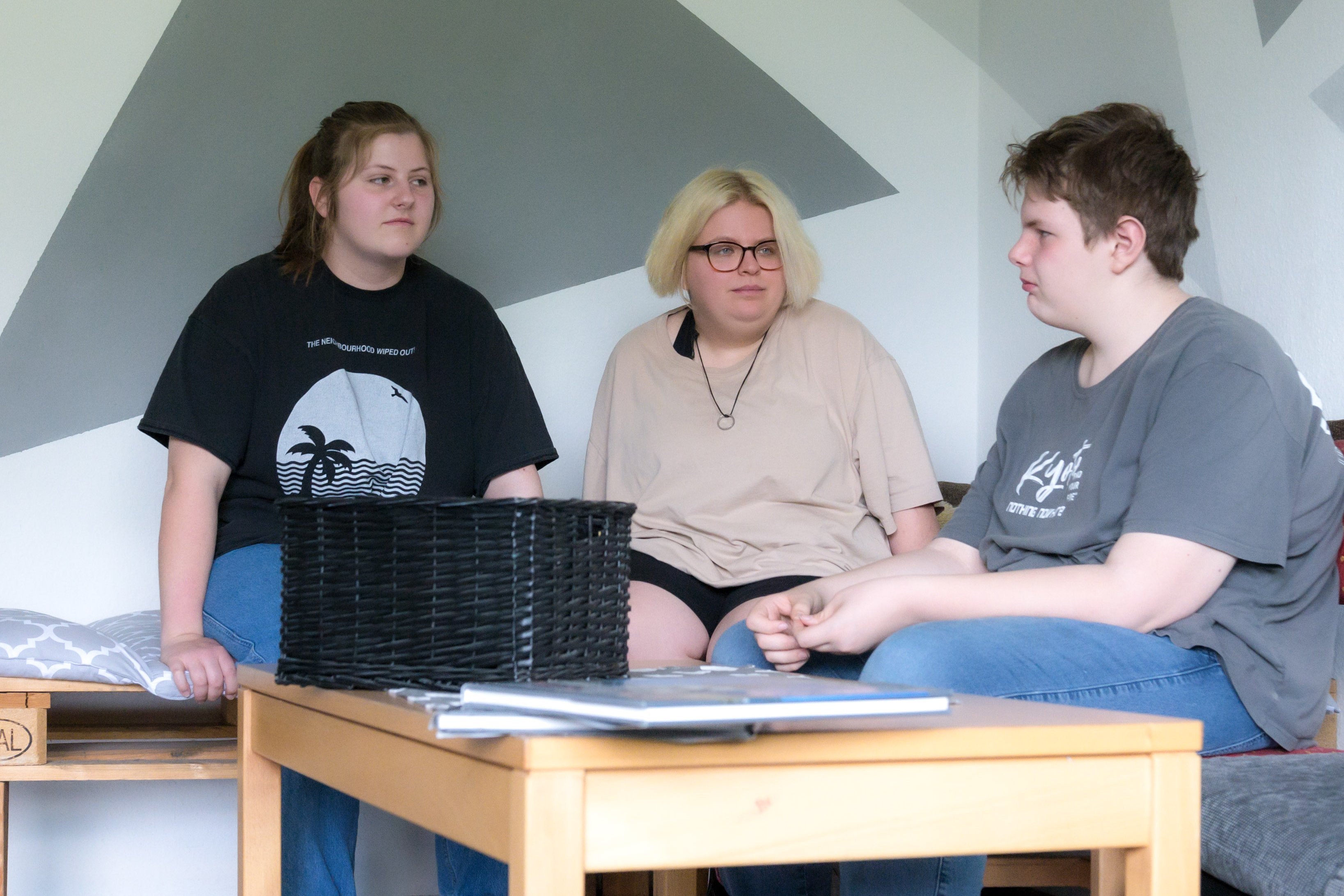 Adipositas Wohngruppen Drei Jugendliche sitzen auf einem Sofa und sprechen miteinander