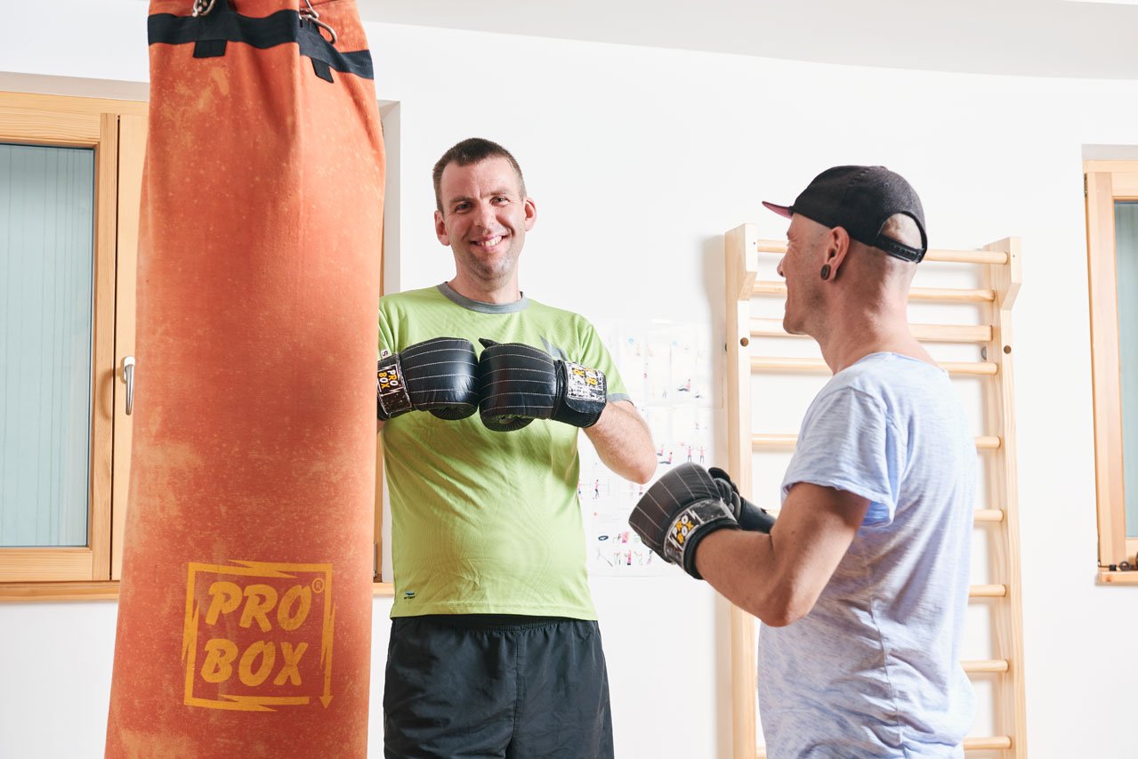 Boxen Zwei Bewohner stehen vor einem Boxsack, beide tragen Boxhandschuhe