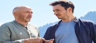 Christian & Felix Neureuther im Gespräch vor einer schönen Bergkulisse zwei Männer reden