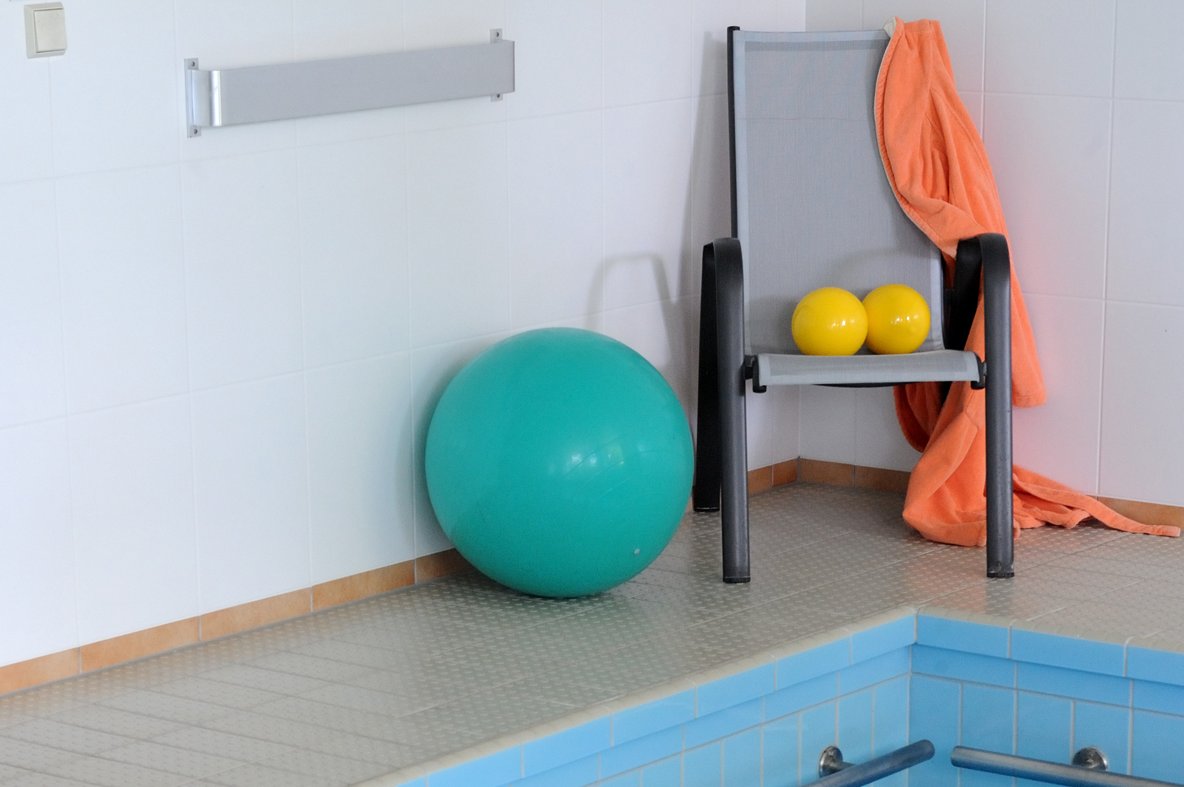 Schwimmen und Wassergymnastik Gymnastikbälle und Stuhl am Rand eines Schwimmbeckens