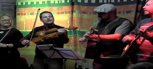 Vier Musiker mit verschiedenen Instrumenten auf einer Bühne