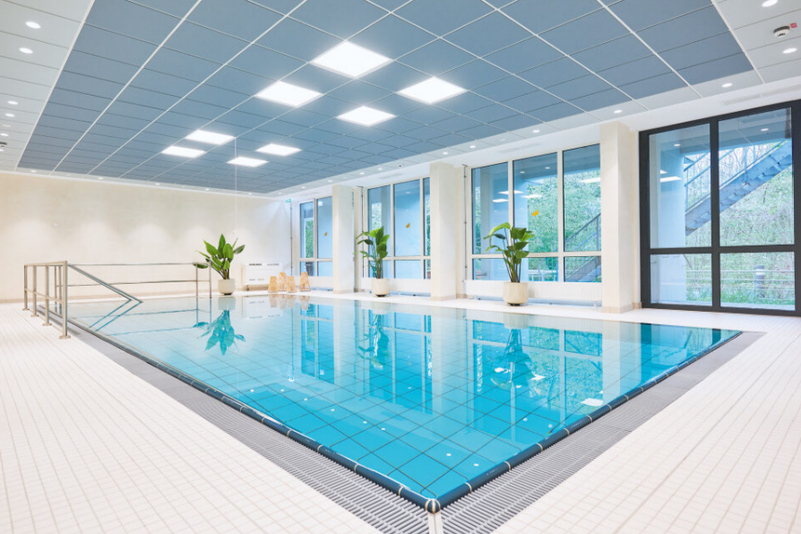 Augustinum Seniorenresidenz Braunschweig Schwimmbad Ein Schwimmbad mit Pflanzen am Beckenrand und großen Fenstern