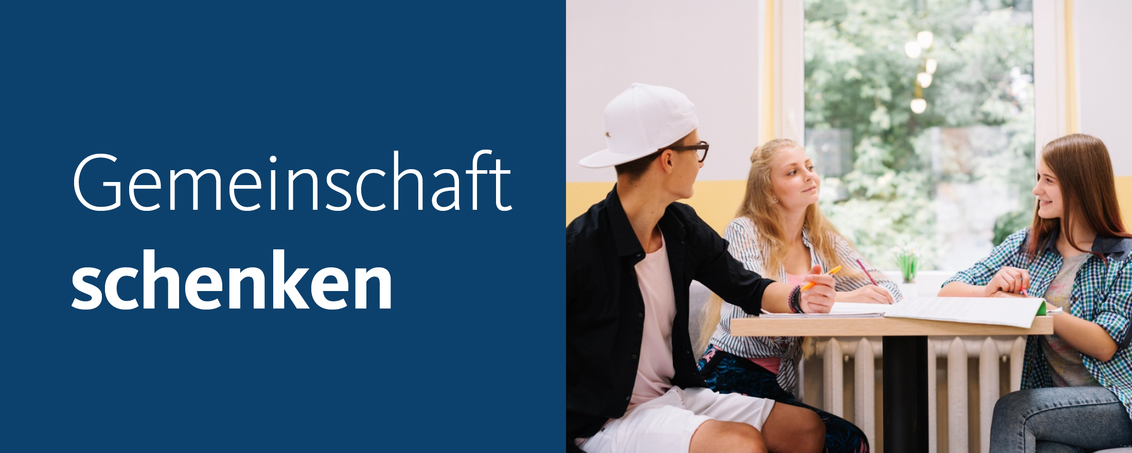 Drei Jugendliche sitzen an einem Tisch und lernen mit Block und Stift