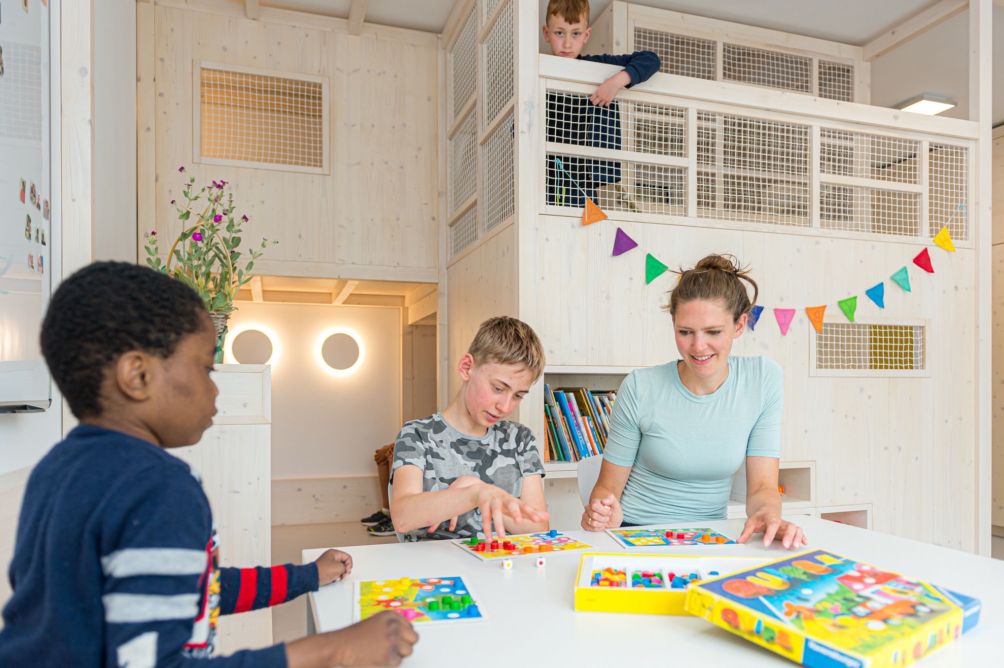 Augustinum Räume für Geborgenheit Kinder spielen gemeinsam mit einer Mitarbeiterin ein Brettspiel