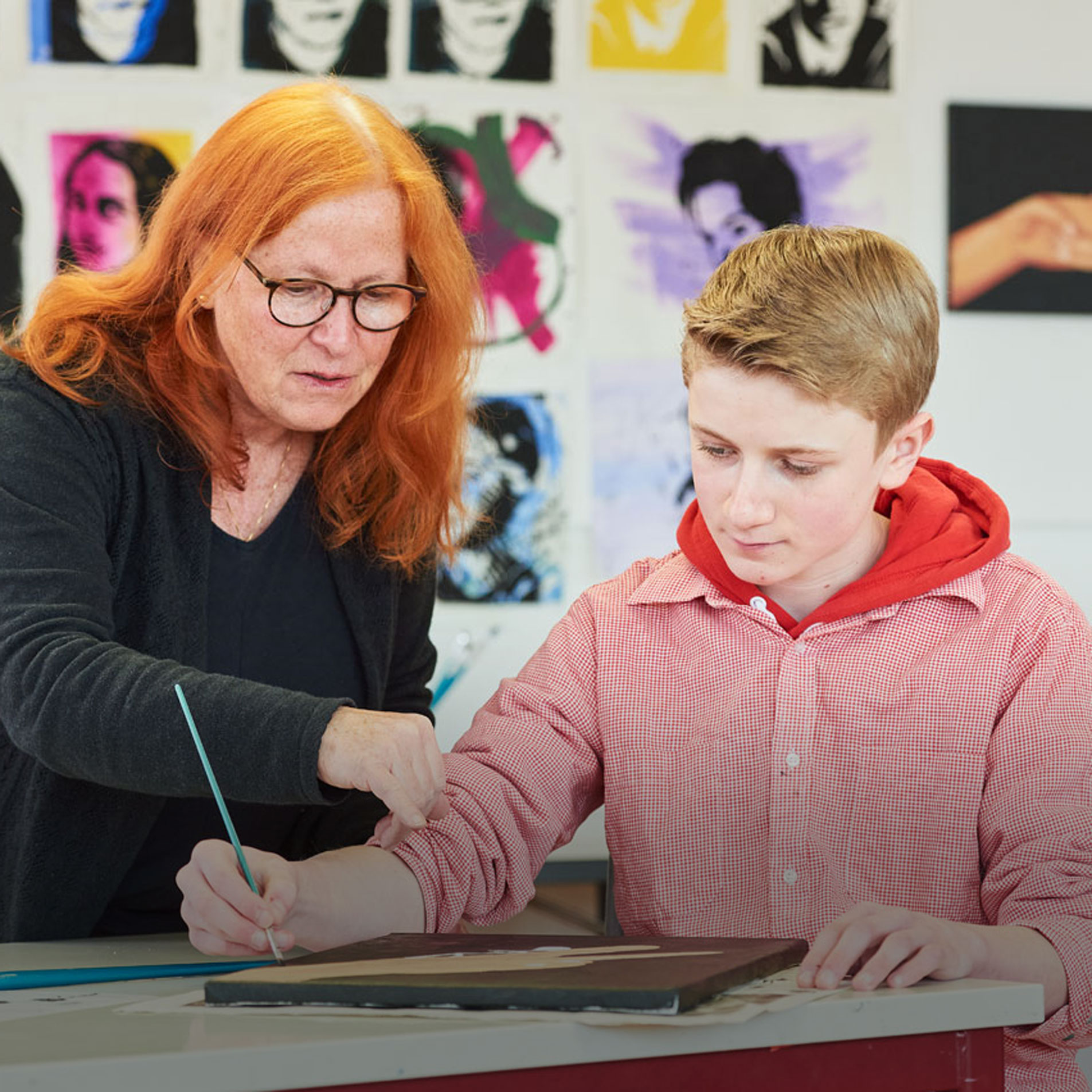 Spenden und Engagement Eine Frau hilft einem Schüler bei einem Kunstprojekt