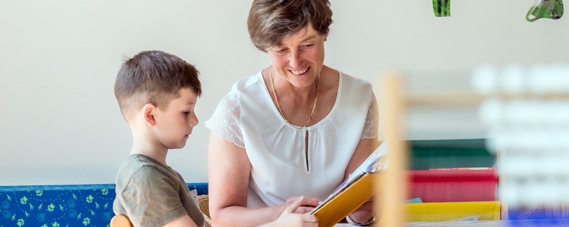 Augustinum Berchtesgadener Land Kindertagesstätte Eine Frau und ein Kind lesen gemeinsam ein Buch