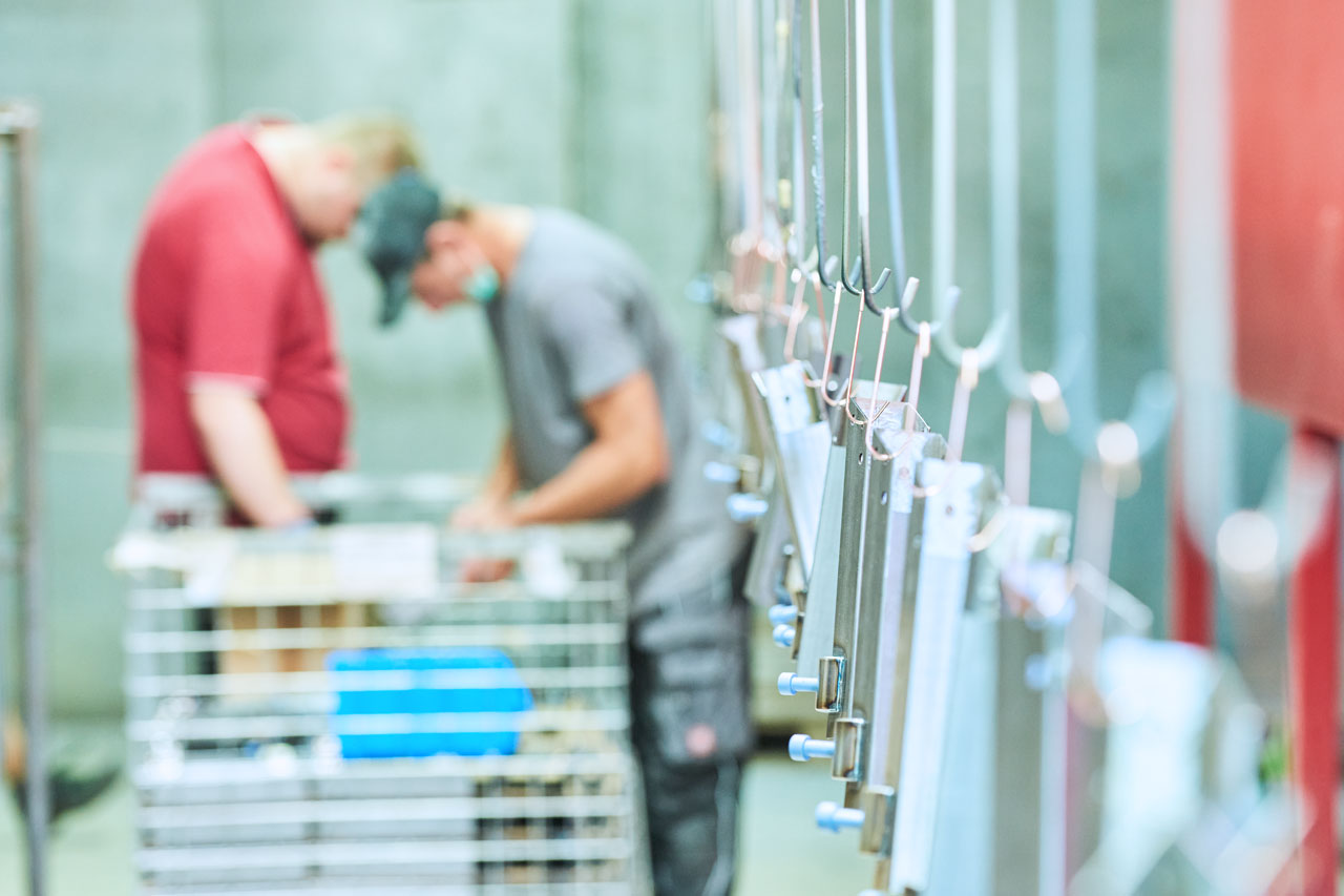 Pulverbeschichtung Zwei Klienten bei ihrer Tätigkeit im Bereich Pulverbeschichtung