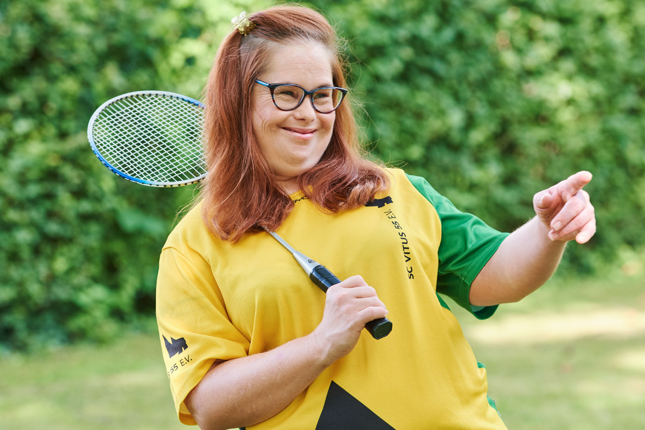 Bewohnerin mit Federballschläger Eine Bewohnerin mit Federballschläger zeigt mit dem Finger nach links