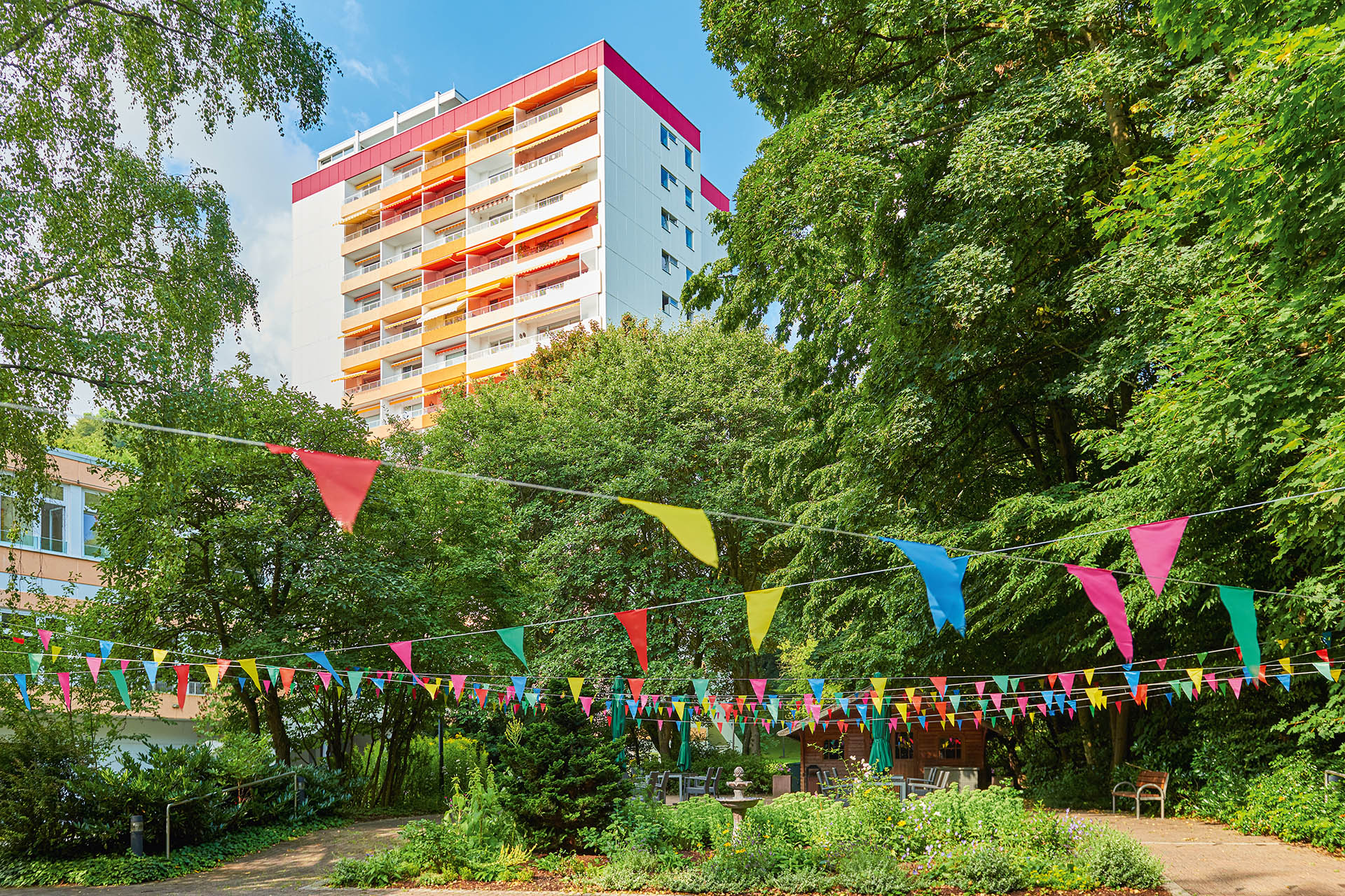 Augustinum Seniorenresidenz Kassel Gartenanlage Eine mit Girlanden beschmückte Gartenanlage und im Hintergrund ist das Augustinum Kassel zu sehen