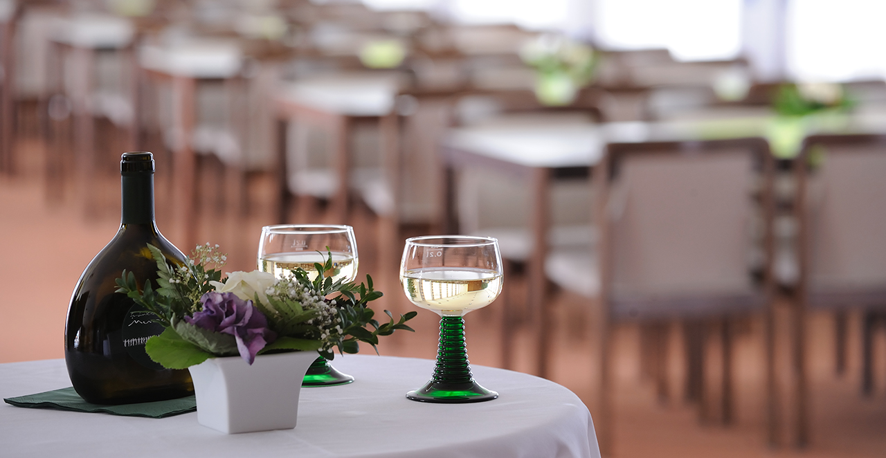 Augustinum Seniorenresidenz Schweinfurt Essen und Genießen Zwei Gläser und ein Blumenstrauß auf einem Tisch im Restaurant