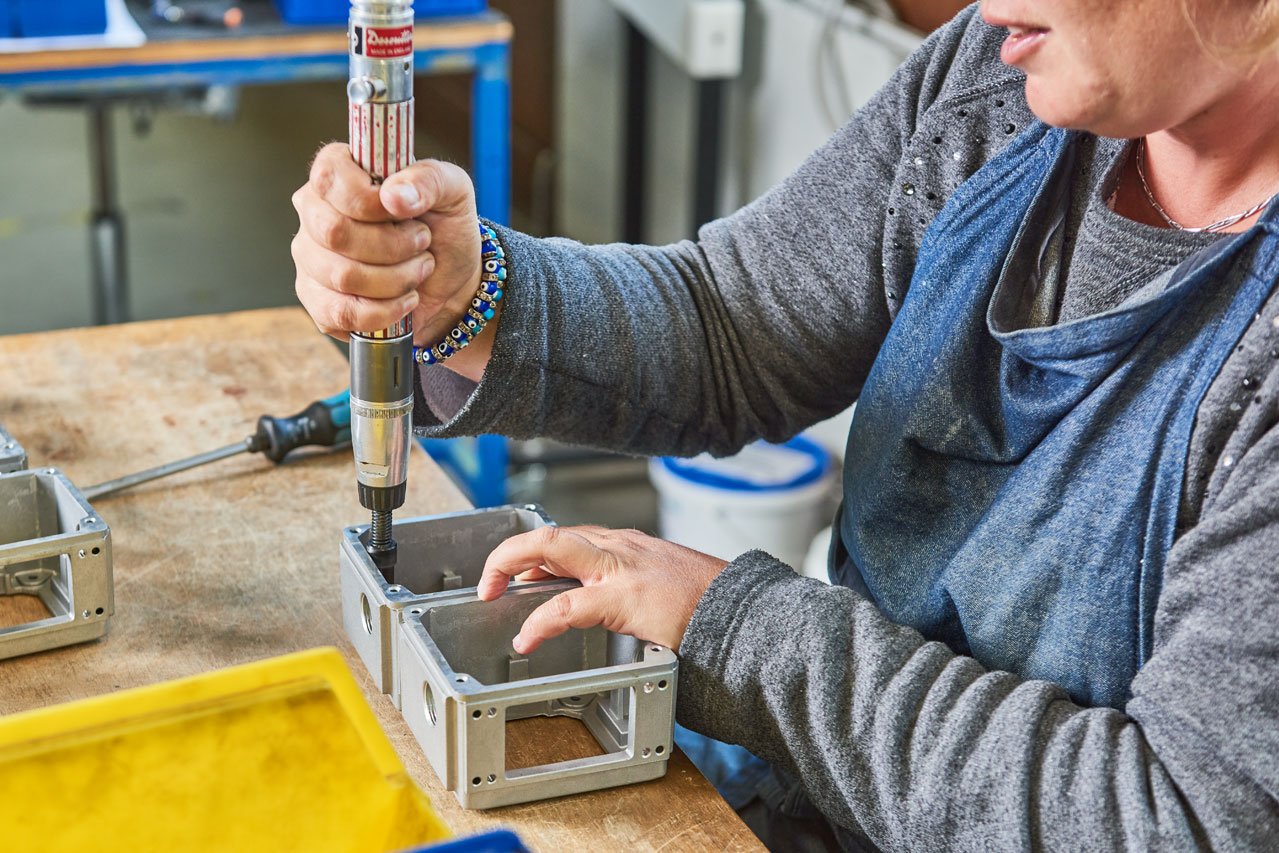 Montieren Eine Klient*in montiert eine Schraube an einem Metallteil