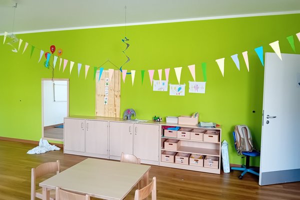 Augustinum Heilpädagogische Tagesstätte Ein großer kindlich dekorierter Raum, in dem Regale und ein Tisch aus Holz stehen