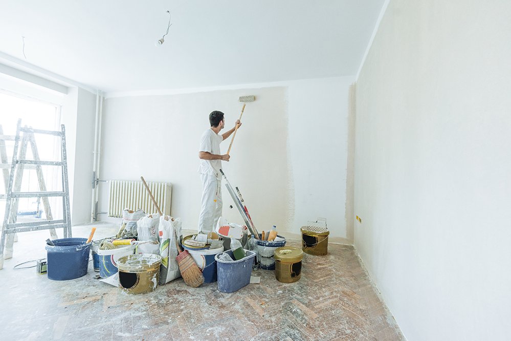 Sie ziehen in eine komplett renovierte Wohnung Ein Maler streich eine Wand weiß