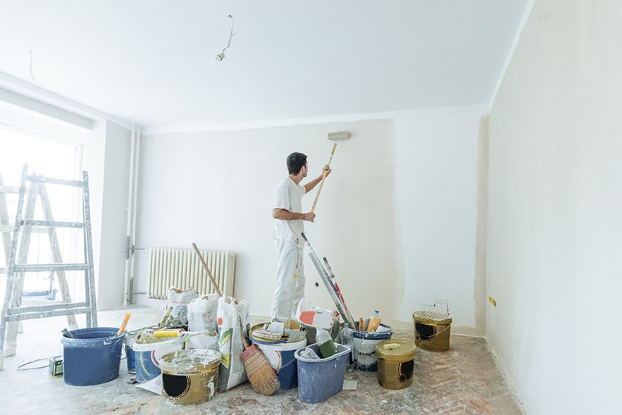 Sie ziehen in eine komplett renovierte Wohnung Ein Maler streich eine Wand weiß
