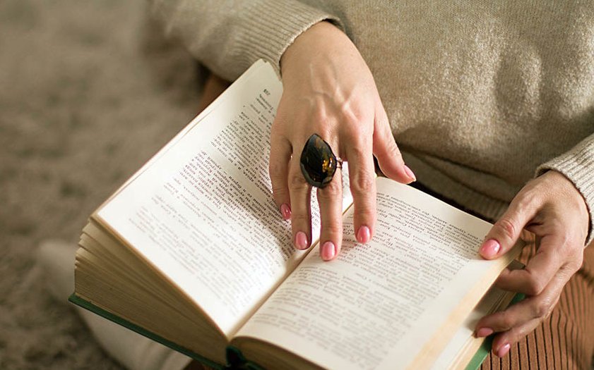 Detailansicht: Hand berührt aufgeschlagenes Buch