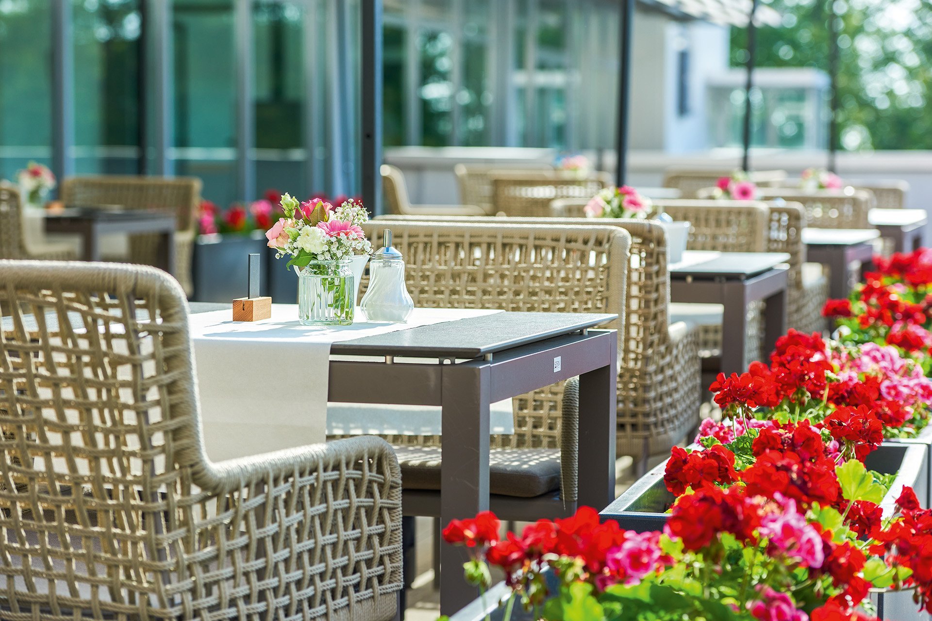 Augustinum Seniorenresidenz Kassel Terrasse Kleine gedeckte Tische auf einer Terrasse mit Blumen-Dekoration