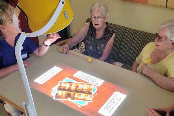 Augustinum Spenden Tovertafel Seniorinnen sitzen an einem Tisch, auf den ein Spiel mithilfe einer Tovertafel projiziert wurde