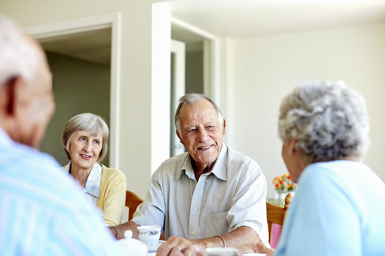 Gruppenunterhaltung   Senior*innen sitzen an einem Tisch und unterhalten sich