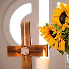 Christliche Werte prägen die Augustinum Gruppe Ein Kreuz und daneben ein Strauß Sonnenblumen auf einem Altar