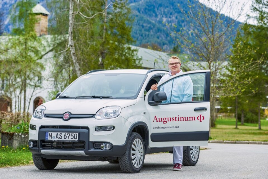 Augustinum Berchtesgadener Land Mobile Pflege Ein Mitarbeiter des ambulanten Pflegedienstes steht an der offenen Tür eines Autos