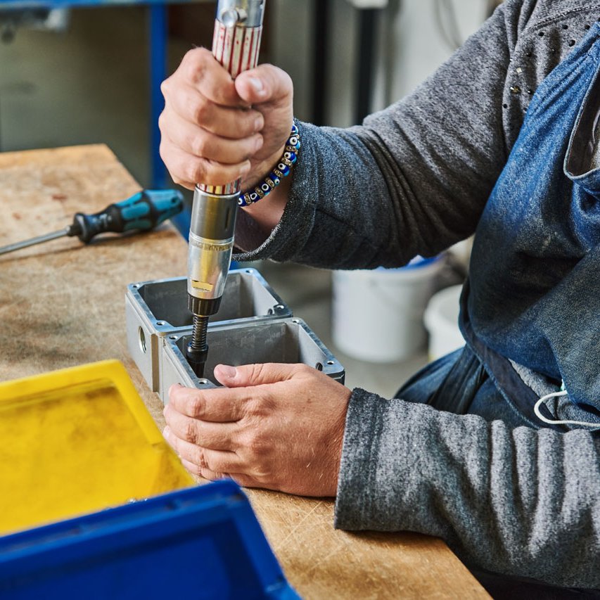 Montieren Eine Klient*in montiert eine Schraube an einem Metallteil