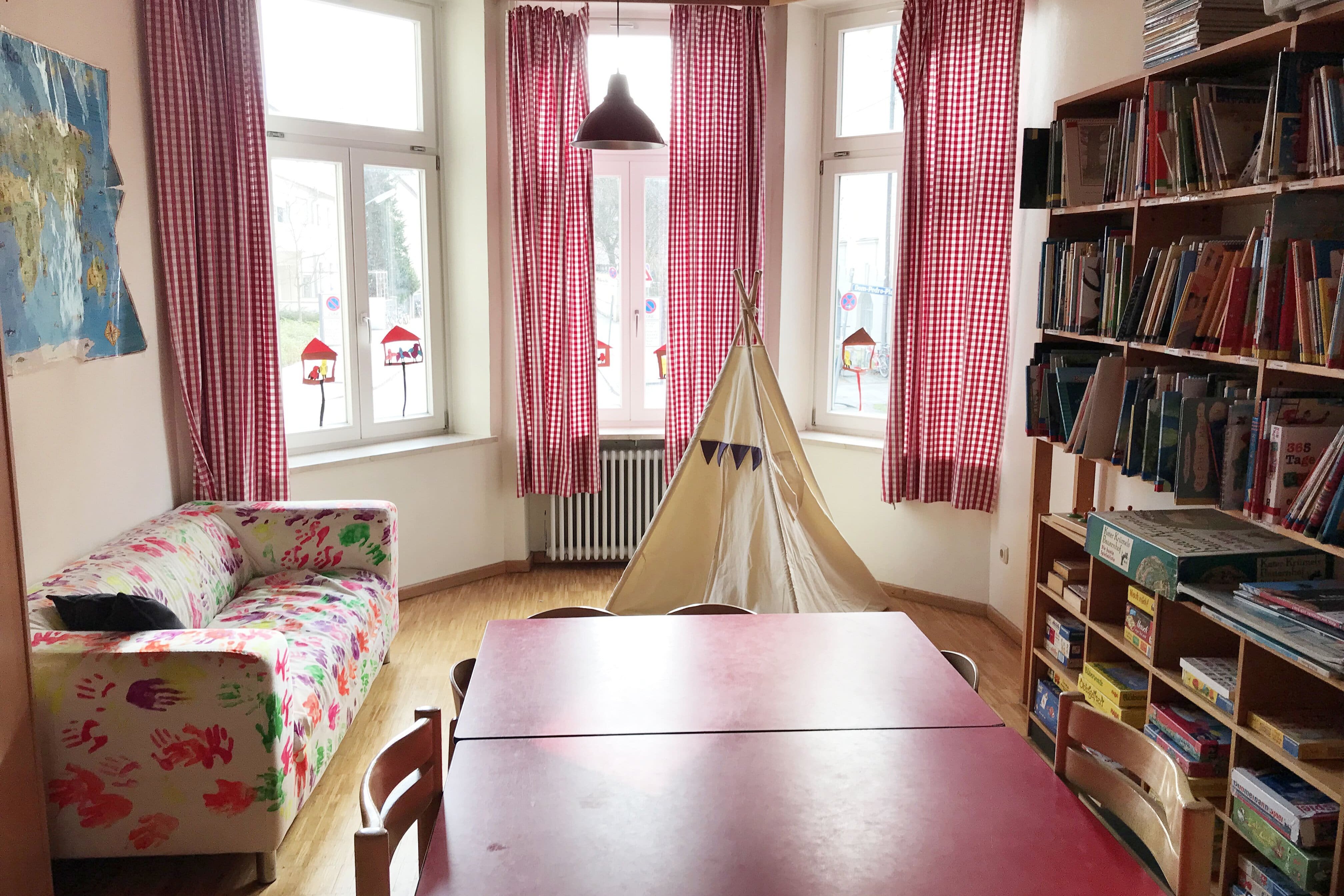 Augustinum Kindergarten Christuskirche Innenraum ein Sofa, ein Tisch und ein Spiel- und Bücherregal im Innenraum des Kindergartens