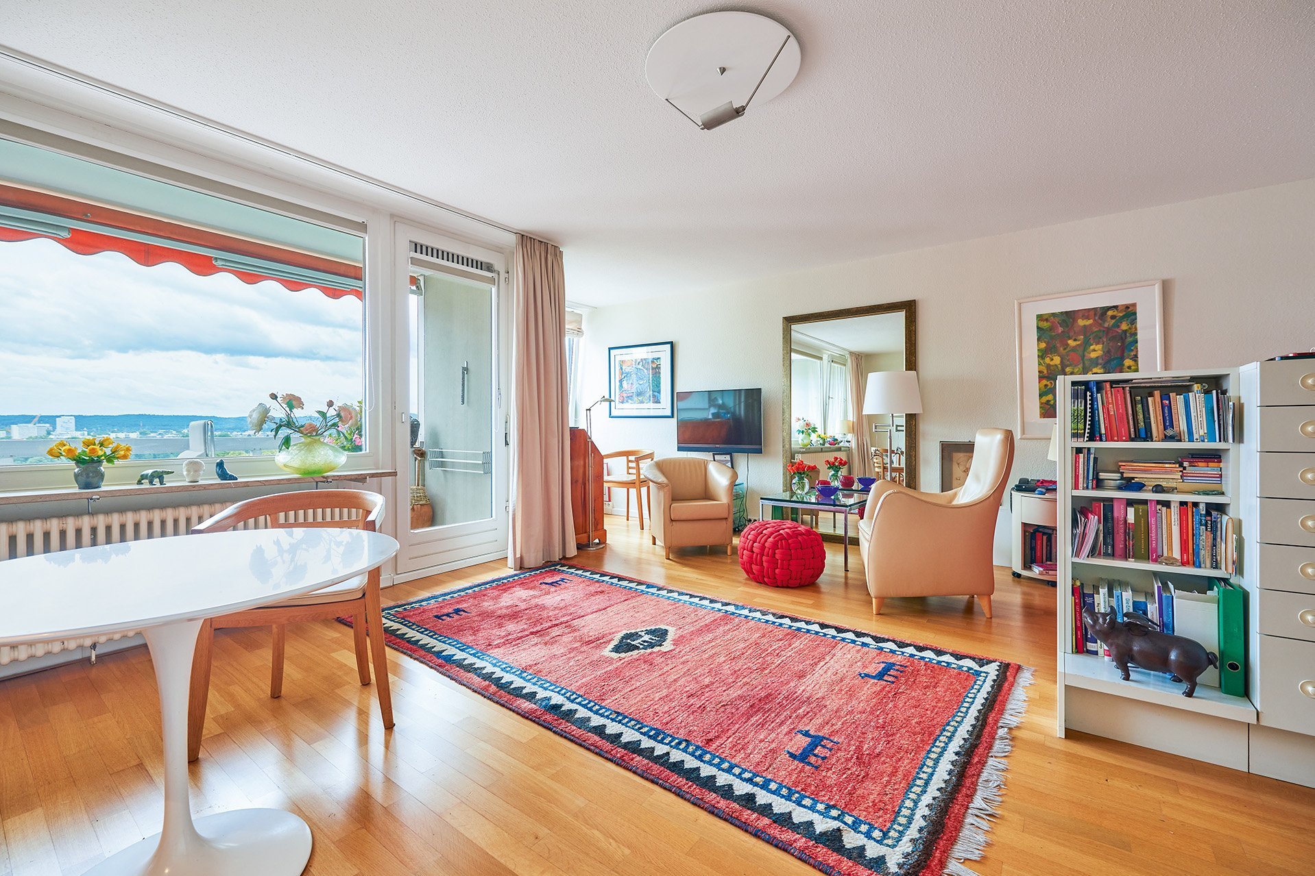 Augustinum Seniorenresidenz Bonn Wohnung Ein großräumiger Wohnbereich mit zwei Sesseln, einem Esstisch und einem Bücherregal