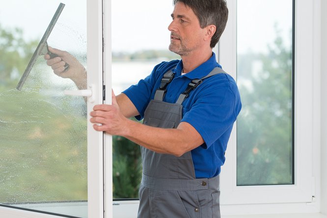 Einmal im Quartal werden die Fenster gereinigt Mann mittleren Alters beim Fensterputzen