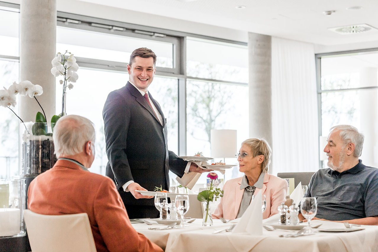 Die Servicemitarbeiter wissen um die Vorlieben ihrer „Stammgäste“. Kellner serviert Gästen am gedeckten Tisch