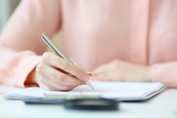 Vorbereitung und Checklisten Hand einer Patientin hält einen Stift beim Ausfüllen eines Formulars