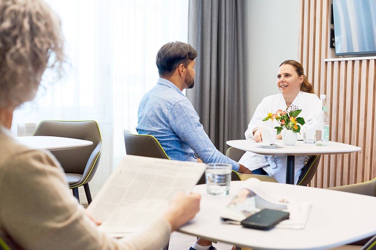 Augustinum Klinik Wahlleistungsstation Lounge Eine Patientin und ein Besucher sitzen an einem Tisch in der Lounge der Wahlleistungsstation