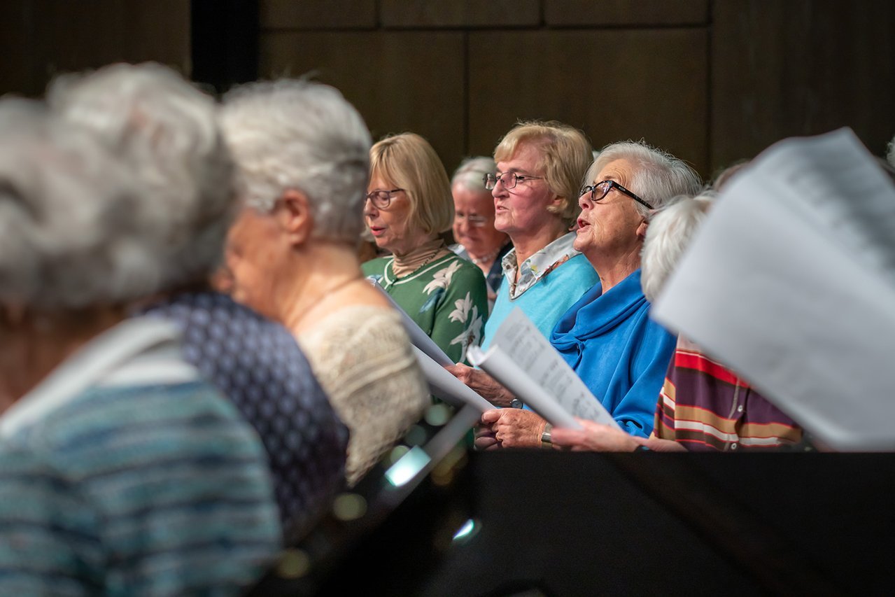 Chor Seniorinnen sitzen in einem Saal und singen